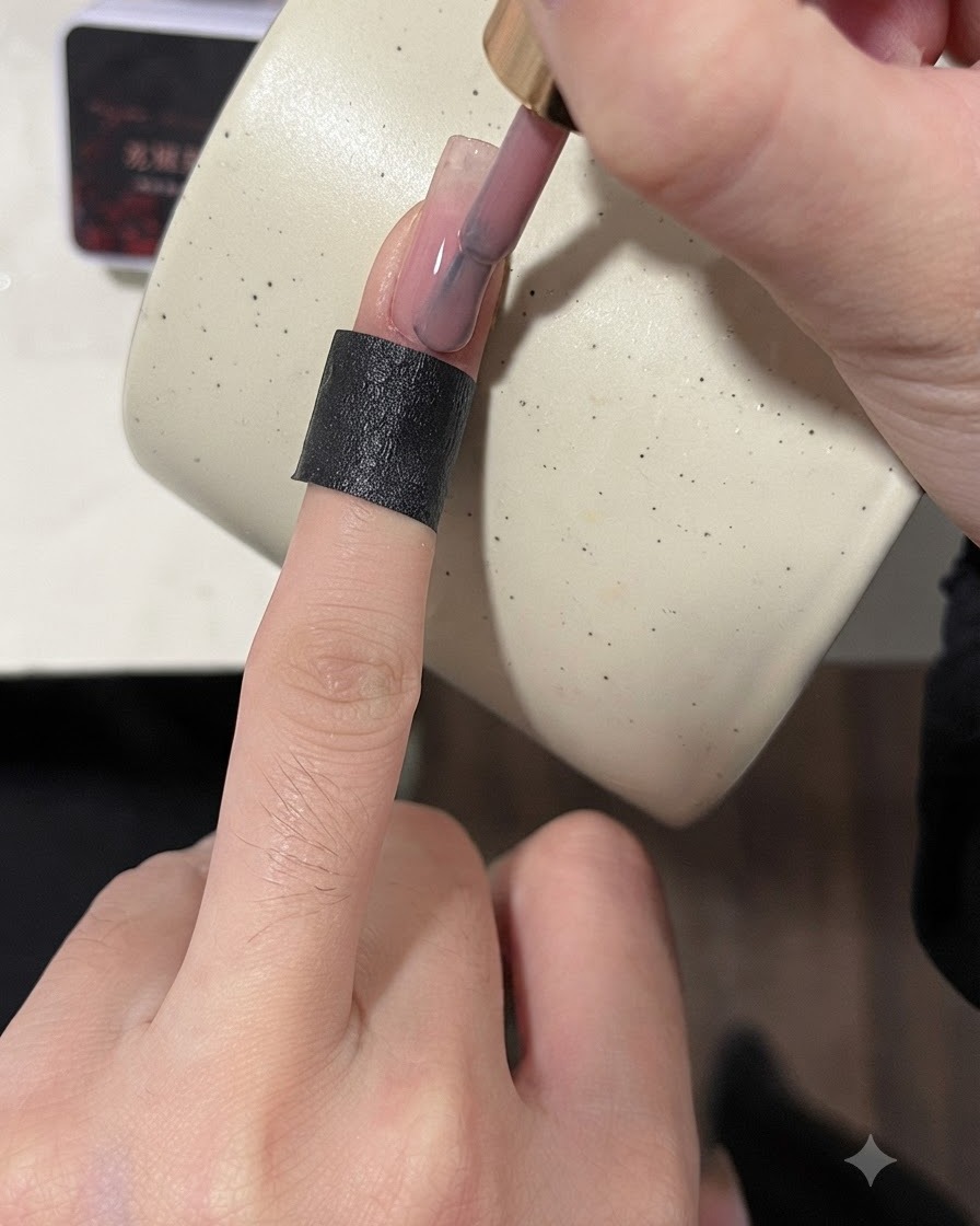 練習用ネイルチップの表面に、ブラシでヌードカラーのベースコートを塗布している様子。