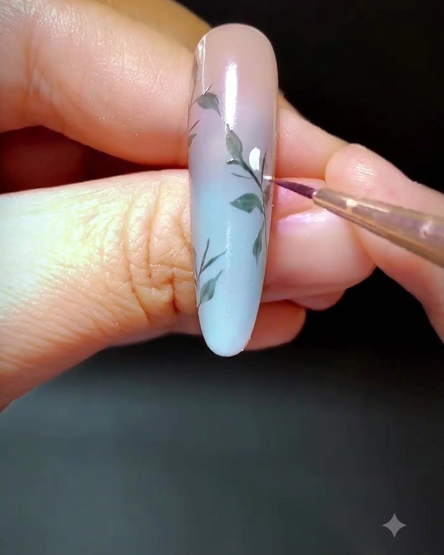 描かれた枝に沿って、白いジェルのドットが置かれている装飾されたネイルのクローズアップ。