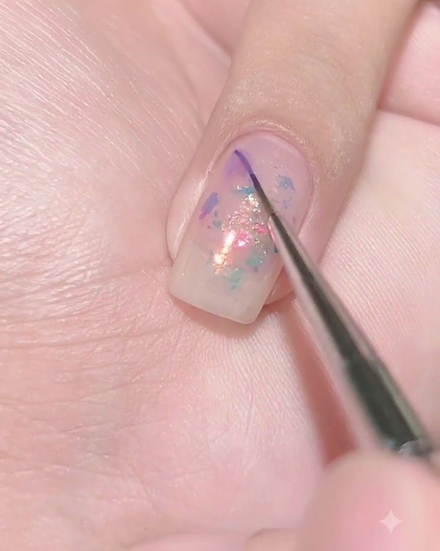 濡れた状態のシアーパープルのネイル表面に、極細のライナーブラシでダークパープルのジェルを小さなドットとして置いている様子。
