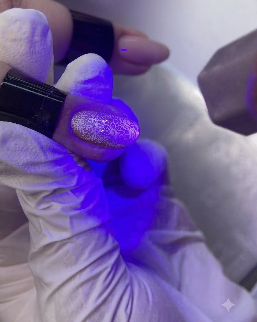 パープル色のUV/LEDネイルランプの下で、装飾された爪を硬化させている手。
