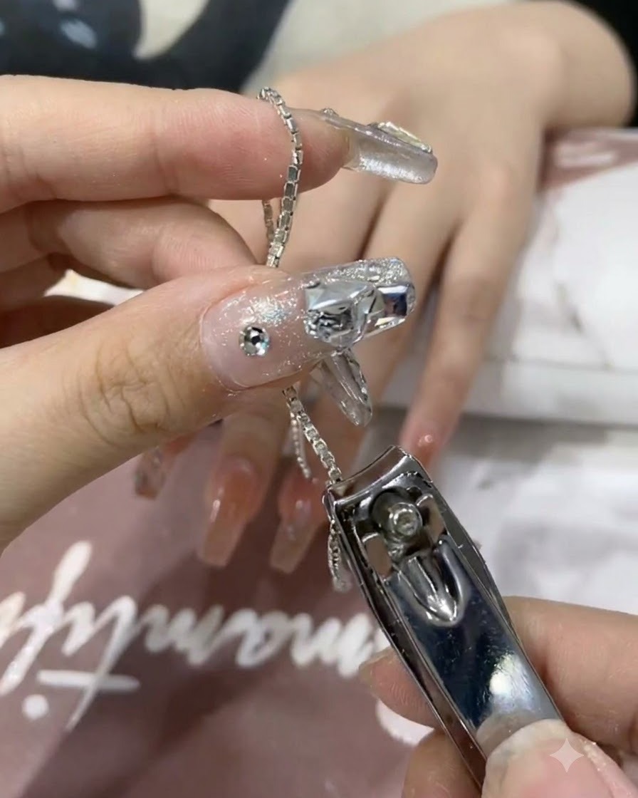 ネイルニッパーで光沢のあるシルバーチェーンの小さなセグメントをカットしているクローズアップ。