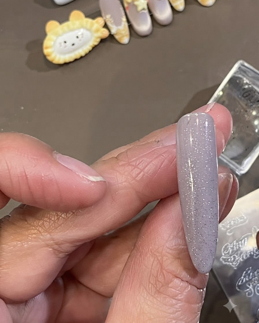 マニキュアが施されたネイルのサイドの皮膚周辺からはみ出した、暗いスタンピングポリッシュを小さなクリーニングブラシで拭き取っているところ。