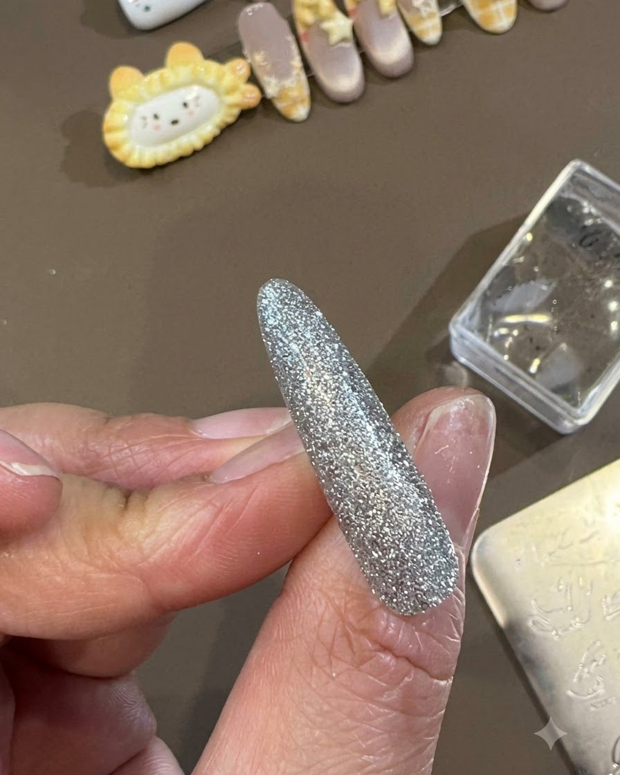 完成したデコレーションネイルの上に、ジェル用トップコートのブラシが滑らかで光沢のあるトップコートの層を滑らせているところ。