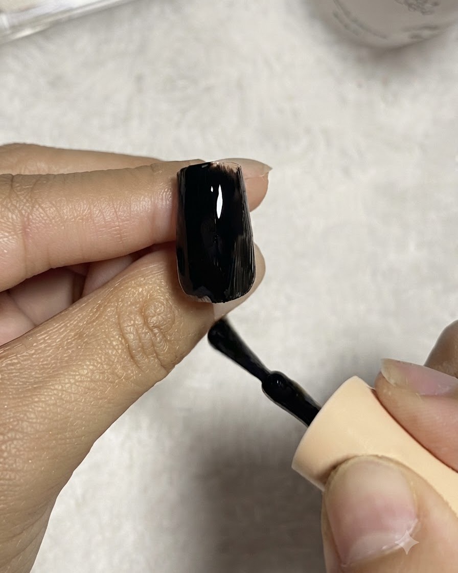 クリアネイルチップの表面に、ネイルブラシで滑らかに黒のジェルポリッシュを塗布している様子。