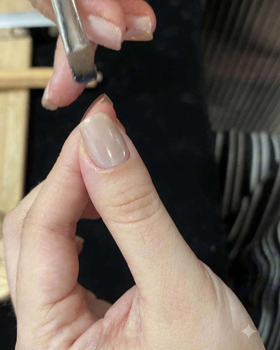 オンブレグラデーションを作るため、ブルーのグラスジェルを含んだ筆を爪の先端の上に構えている状態。